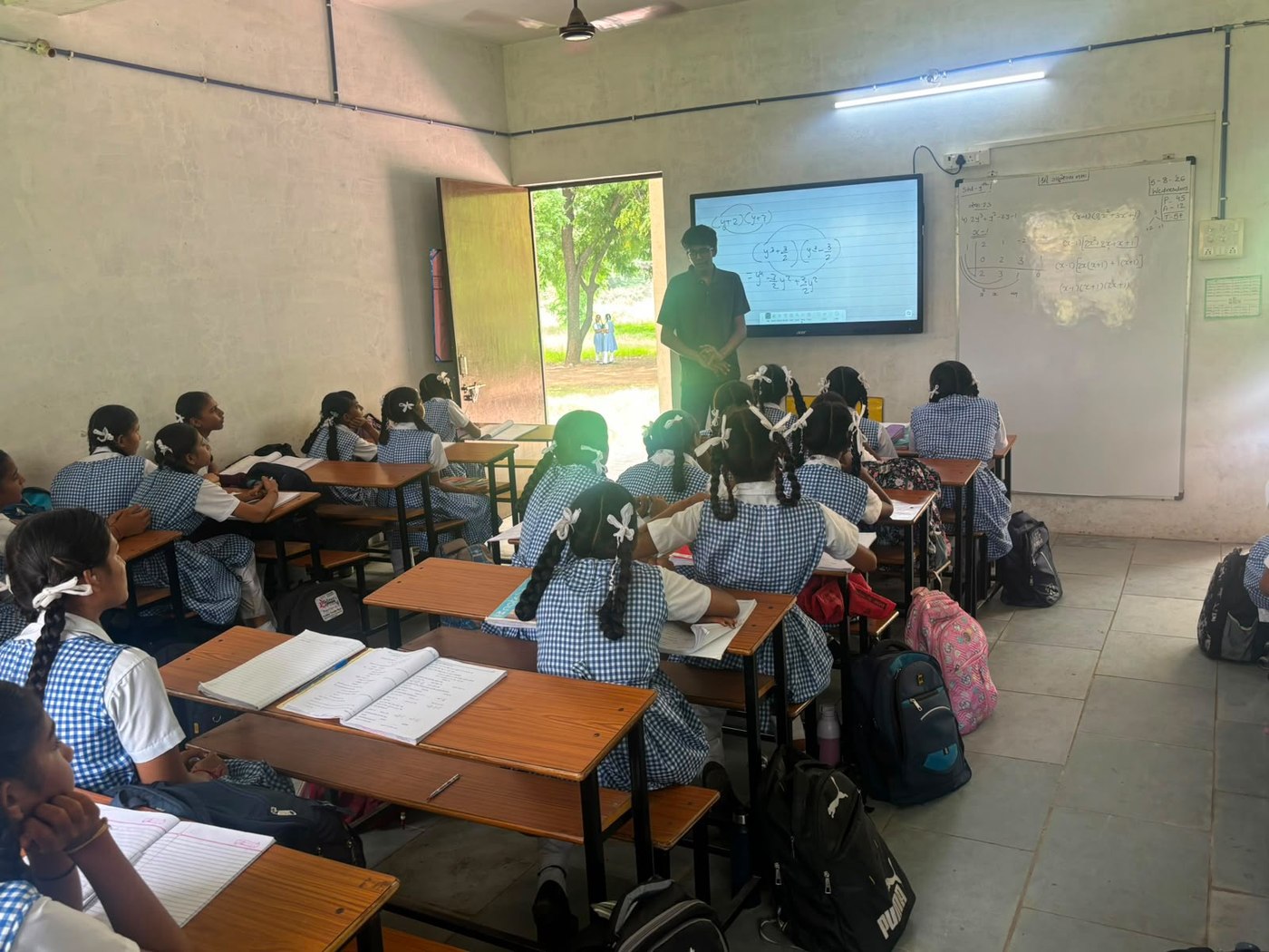Rishabh at the smart board with students seated in rows